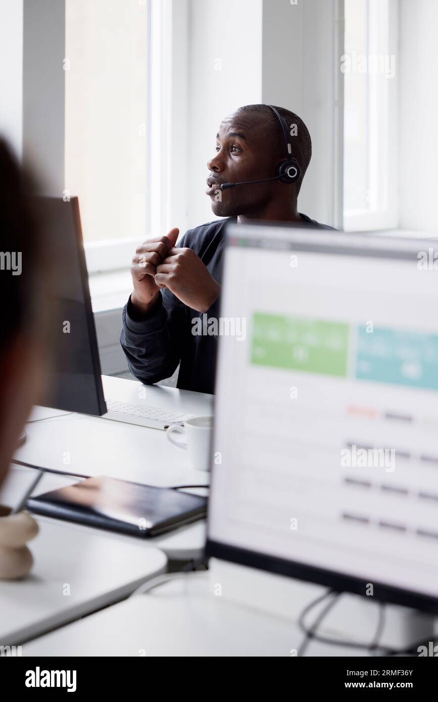 Mature businessman using headset and while sitting in office Stock Photo