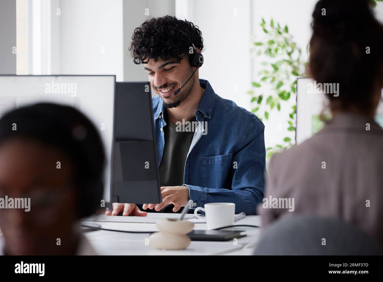 Young man using headset while sitting in office Stock Photo