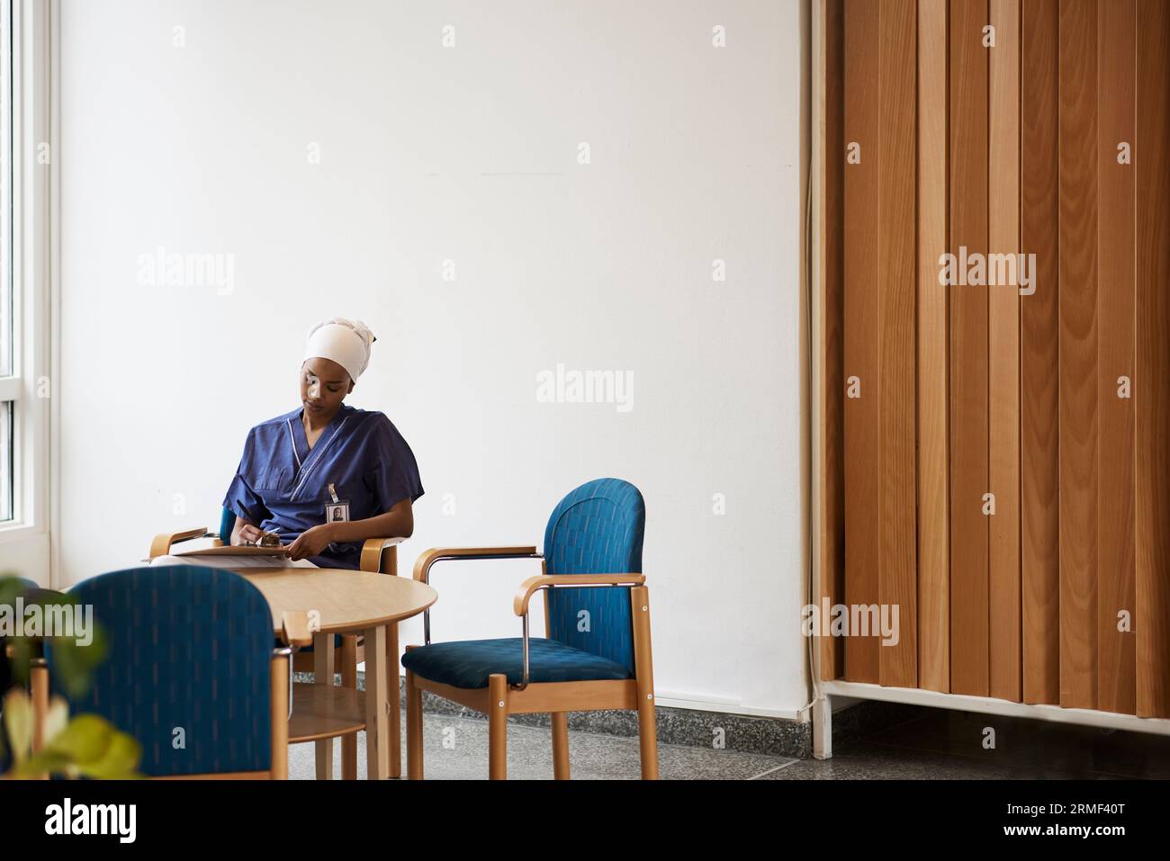 Female doctor sitting at table and taking notes Stock Photo