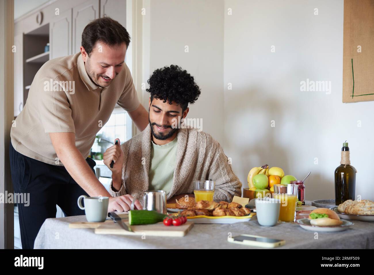 Happy gay couple eating breakfast at home Stock Photo