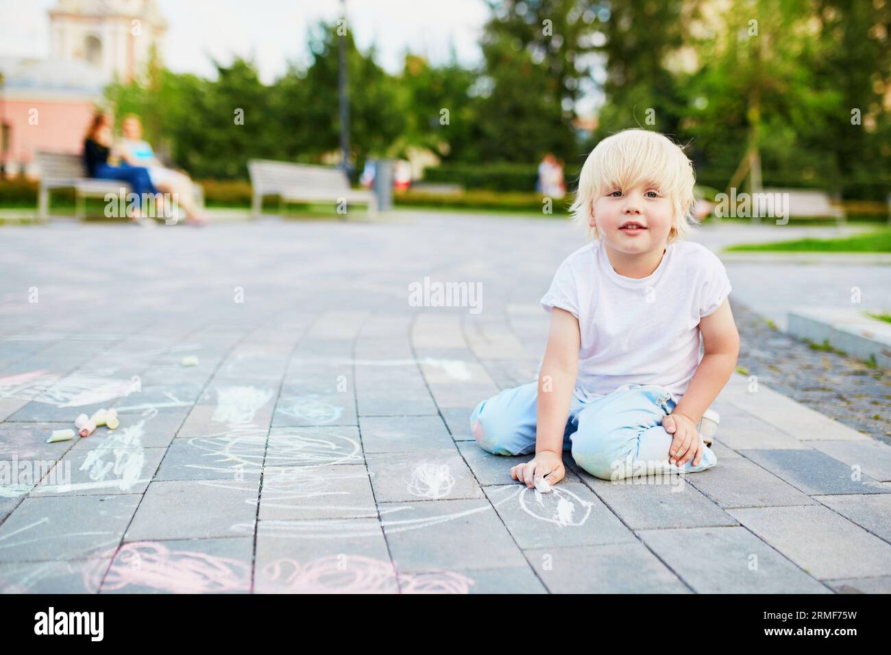 Adorable little boy drawing with colorful chalks on asphalt. Summer ...