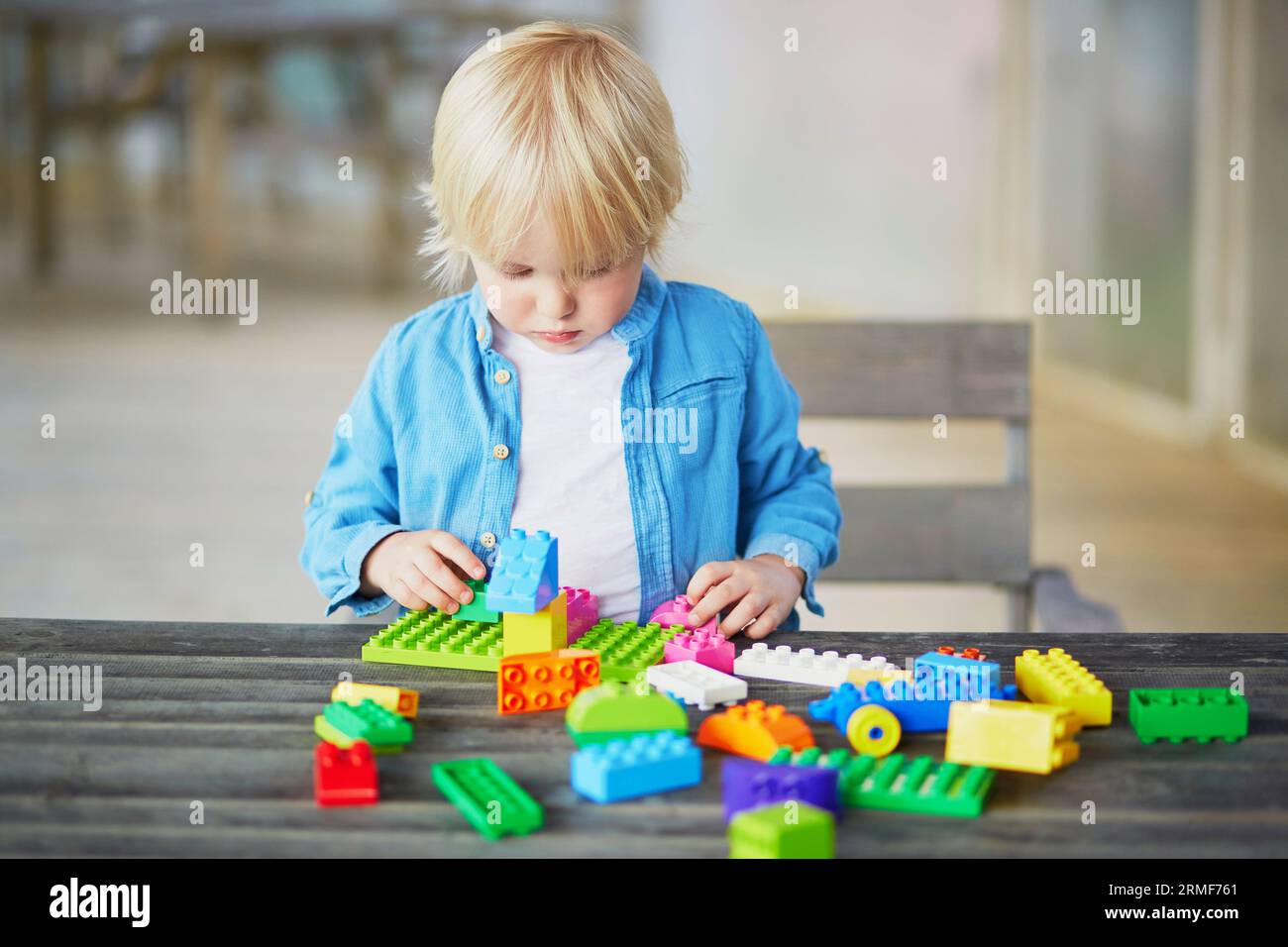 Adorable little boy playing with colorful plastic construction blocks ...