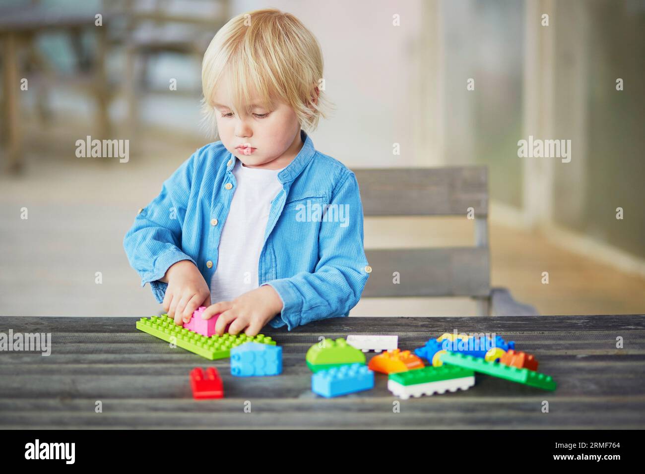 Adorable little boy playing with colorful plastic construction blocks ...