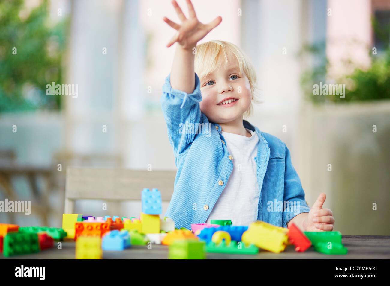 Adorable little boy playing with colorful plastic construction blocks ...
