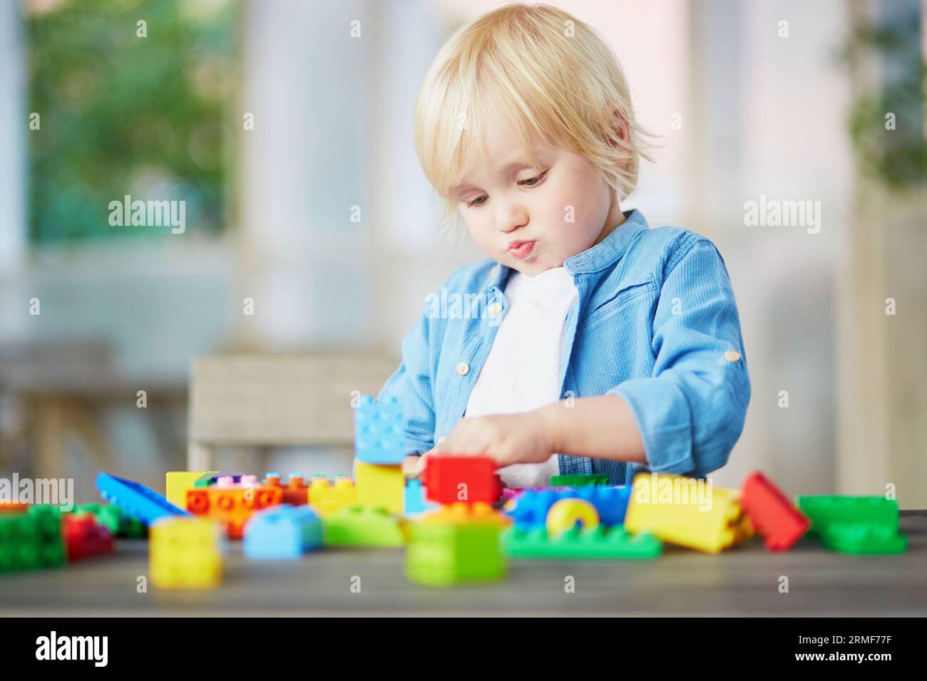 Adorable little boy playing with colorful plastic construction blocks ...