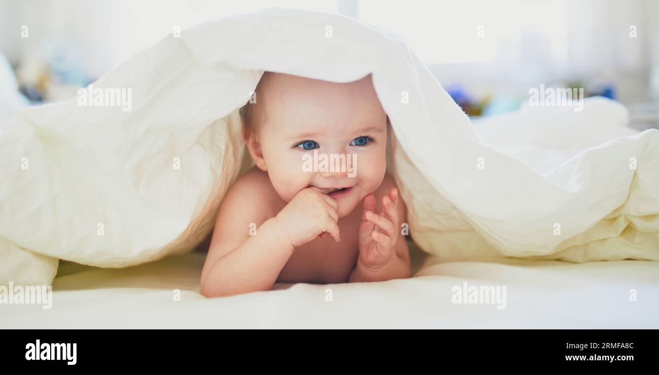 Cute little girl playing on bed. Happy kid having fun in nursery. Baby