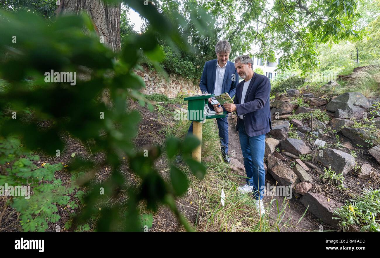 28 August 2023, Saxony-Anhalt, Halle (Saale): Matthias Lux (l), Managing Director of Stadtwerke Halle, and Andreas Nowak, Managing Director of Mitteldeutsches Multimediazentrum, open the new Harzer Wandernadel stamp station in the Botanical Garden in Halle/Saale. Both are passionate hikers and in possession of a hiking pass. Hikers will find a total of over 400 stamping stations in Saxony-Anhalt, Lower Saxony and Thuringia. The stamps are pressed into a previously purchased hiking passport. 222 stamp impressions are necessary to become the 'Harzer Wanderkaiser' or 'Wanderkaiserin'. Photo: Hend Stock Photo