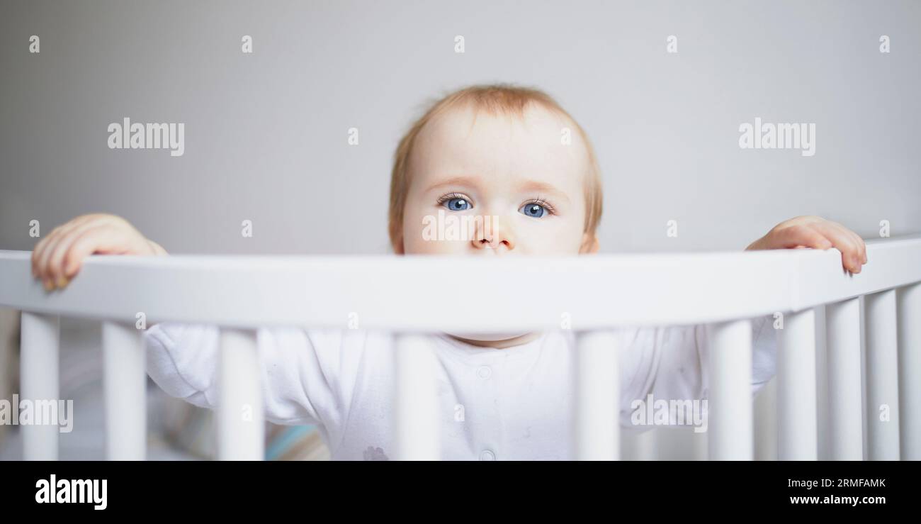Adorable baby girl in cosleeper crib attached to parents bed. Little