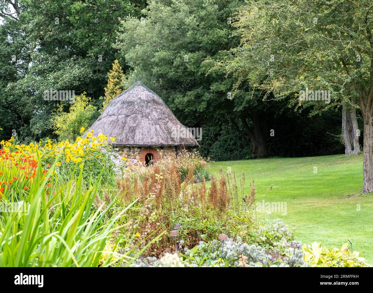 Bressingham, Norfolk, UK – August 21 2023. Summer house with thatched roof in a tranquil and picturesque flower garden Stock Photo