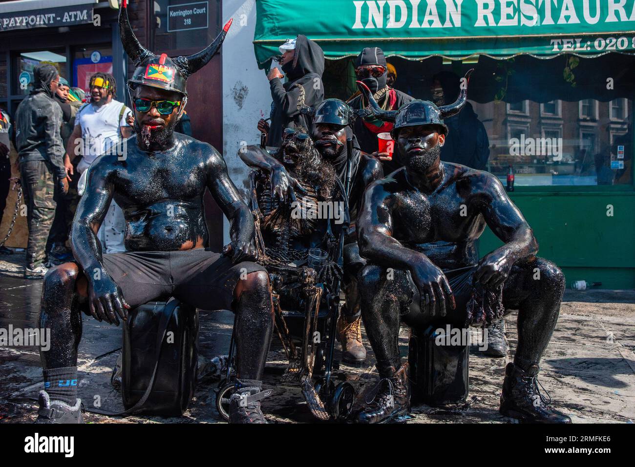 Black-painted men pose for a photo. It used to be black oil but they  replaced it with black paint to cover the body. The Notting Hill Carnival  is one of the biggest