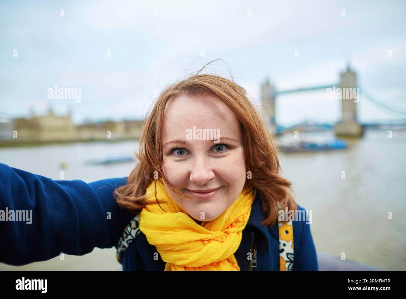 Tourist taking a funny self picture (selfie) with Tower bridge in