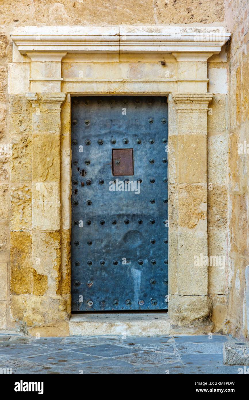 Metallic door on an antique stone wall. Stock Photo