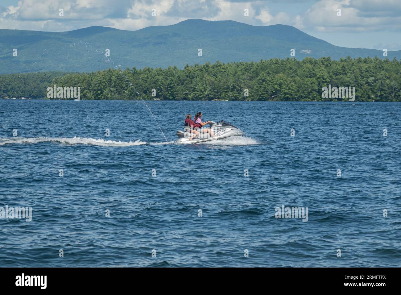 Two people riding a jet ski on Lake Winnipesaukee in New Hampshire