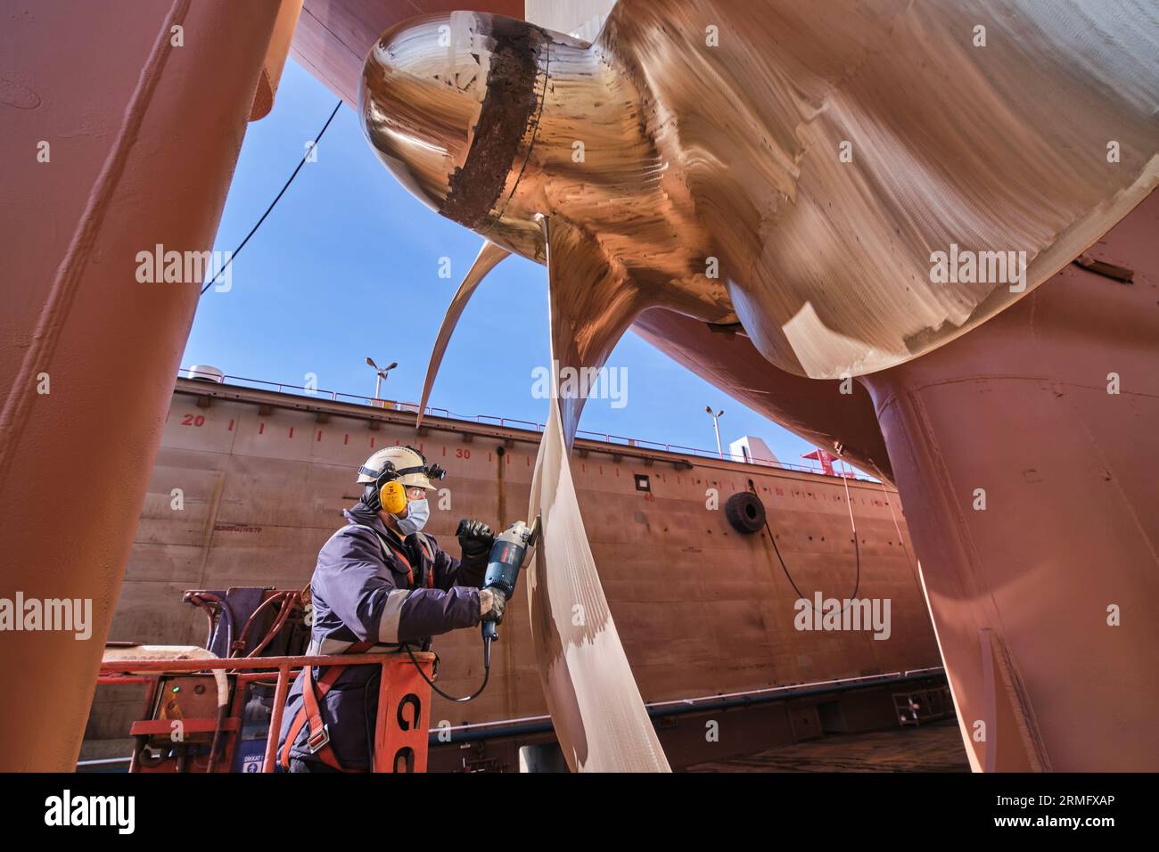 man repairing a ship propeller using a handheld saw .propeller ship