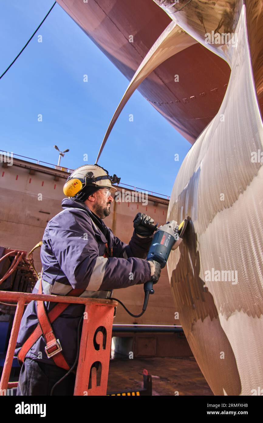 man repairing a ship propeller using a handheld saw .propeller ship