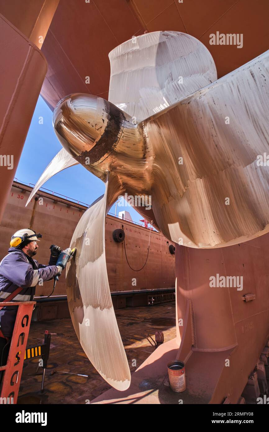 man repairing a ship propeller using a handheld saw .propeller ship