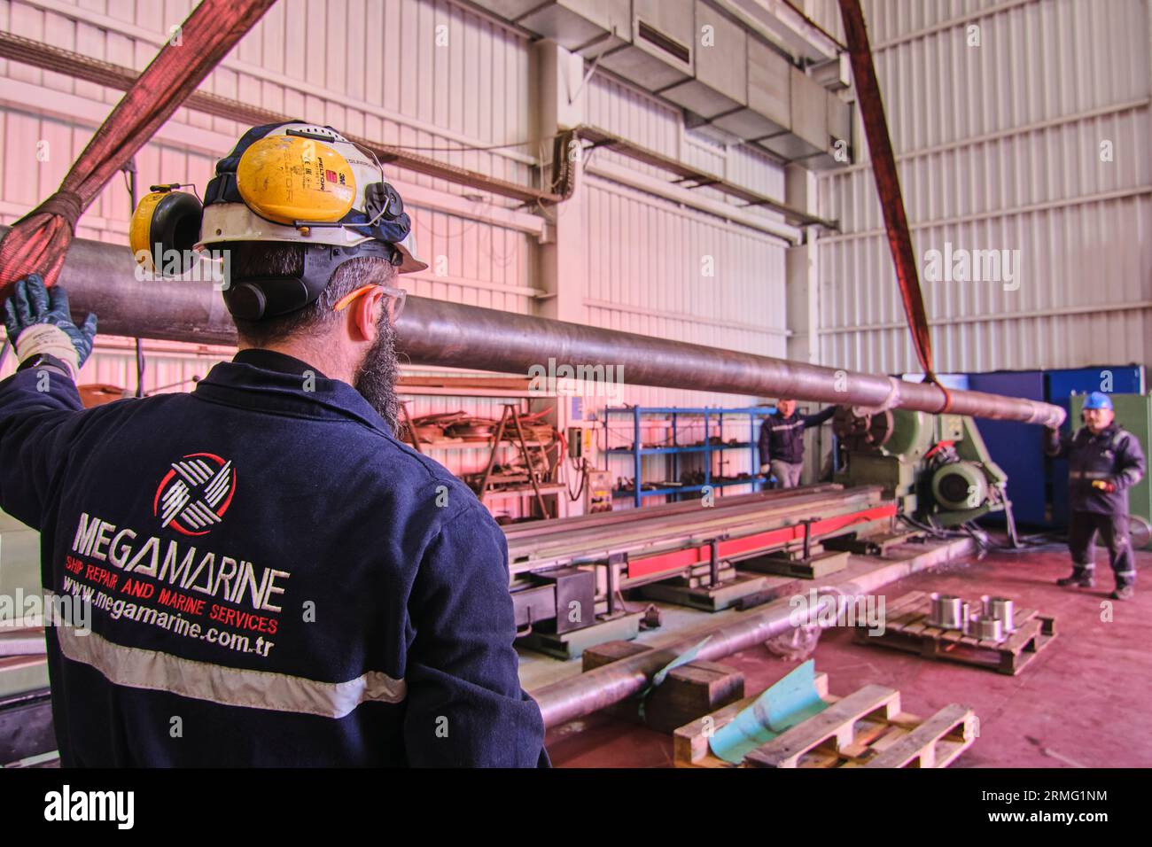 men using a lift and a crane to move big, heavy metal objects like pips ...