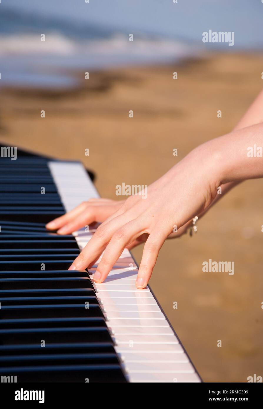 Playing music at the seashore. Beautiful female hands, piano keyboard and  ocean or sea in the background Stock Photo - Alamy