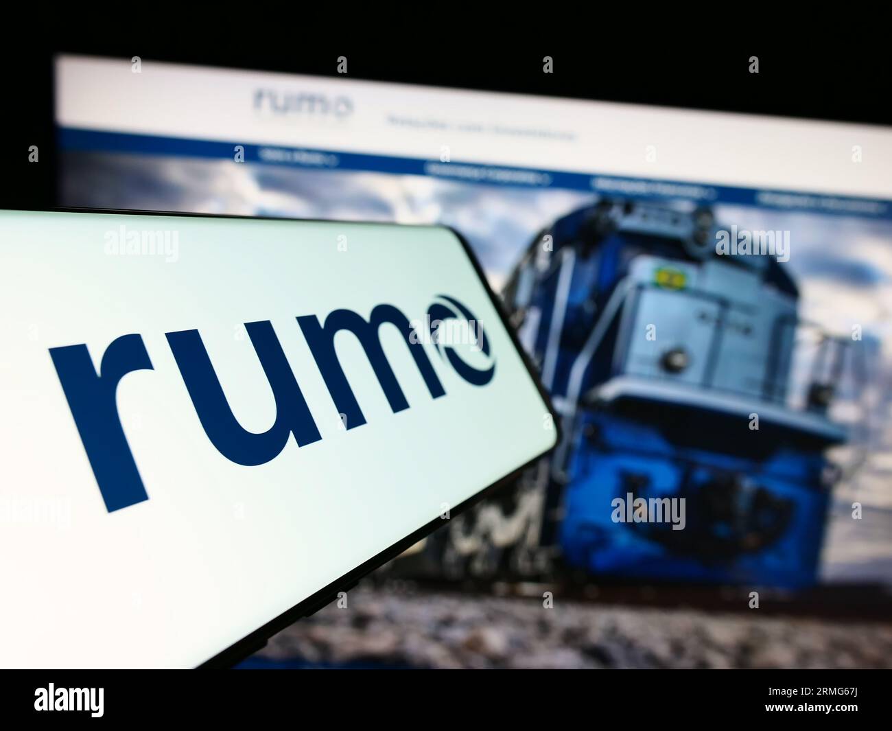 Cellphone with logo of Brazilian logistics company Rumo S.A. on screen in front of business website. Focus on center-left of phone display. Stock Photo