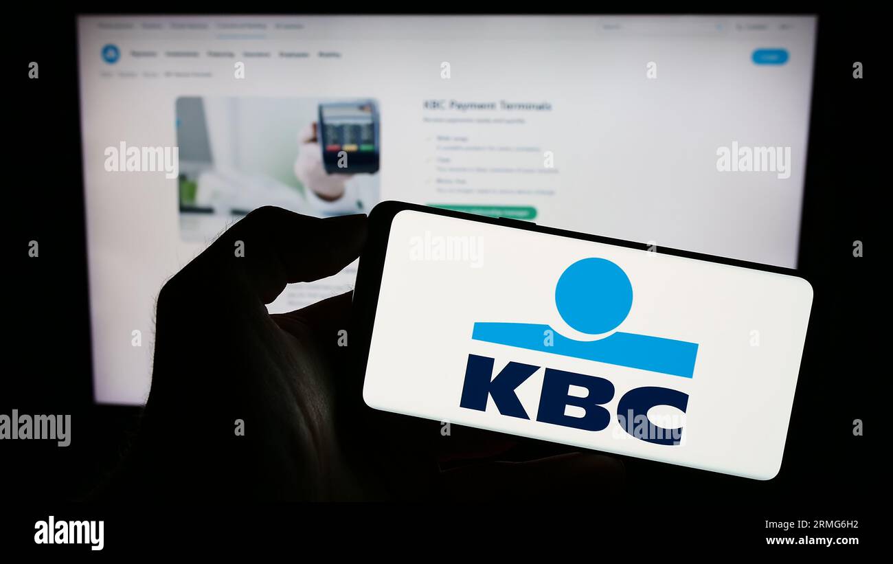 Person holding smartphone with logo of Belgian financial company KBC Group N.V.  on screen in front of website. Focus on phone display. Stock Photo