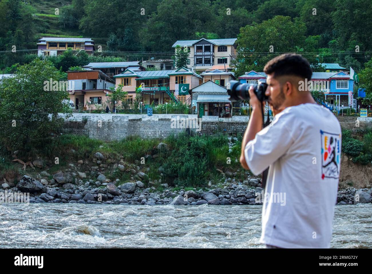Keran Kupwara, India. 24th Aug, 2023. A Photographer takes photos towards Pakistan Administered Kashmir on the banks of Neelam river or Kishan Ganga that has divided Kashmir into two parts controlled by nuclear rivals India and Pakistan. The river acts as a disputed line of control and flows through a village called Keran from both sides which is located on the northern side of Indian Kashmir's Border district Kupwara some 150kms from Srinagar and 93kms from Muzaffarabad, in the Pakistan side of Kashmir. (Photo by Faisal Bashir/SOPA Images/Sipa USA) Credit: Sipa USA/Alamy Live News Stock Photo