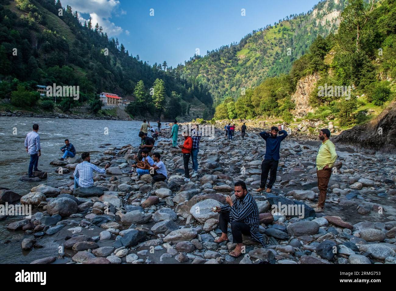 Keran Kupwara, India. 24th Aug, 2023. People are seen relaxing on the banks of Neelam river or Kishan Ganga that has divided Kashmir into two parts controlled by nuclear rivals India and Pakistan. The river acts as a disputed line of control and flows through a village called Keran from both sides which is located on the northern side of Indian Kashmir's Border district Kupwara some 150kms from Srinagar and 93kms from Muzaffarabad, in the Pakistan side of Kashmir. (Photo by Faisal Bashir/SOPA Images/Sipa USA) Credit: Sipa USA/Alamy Live News Stock Photo