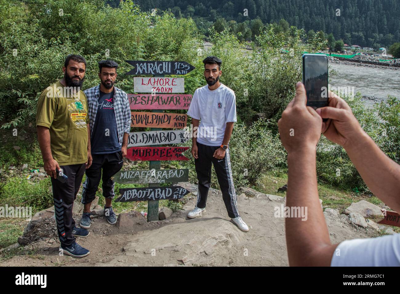 A man takes photos of his friends in-front of kilometer sign board which is installed in Indian administered Kashmir on the banks of Neelam river or Kishan Ganga that has divided Kashmir into two parts controlled by nuclear rivals India and Pakistan. The river acts as a disputed line of control and flows through a village called Keran from both sides which is located on the northern side of Indian Kashmir's Border district Kupwara some 150kms from Srinagar and 93kms from Muzaffarabad, in the Pakistan side of Kashmir. (Photo by Faisal Bashir/SOPA Images/Sipa USA) Stock Photo