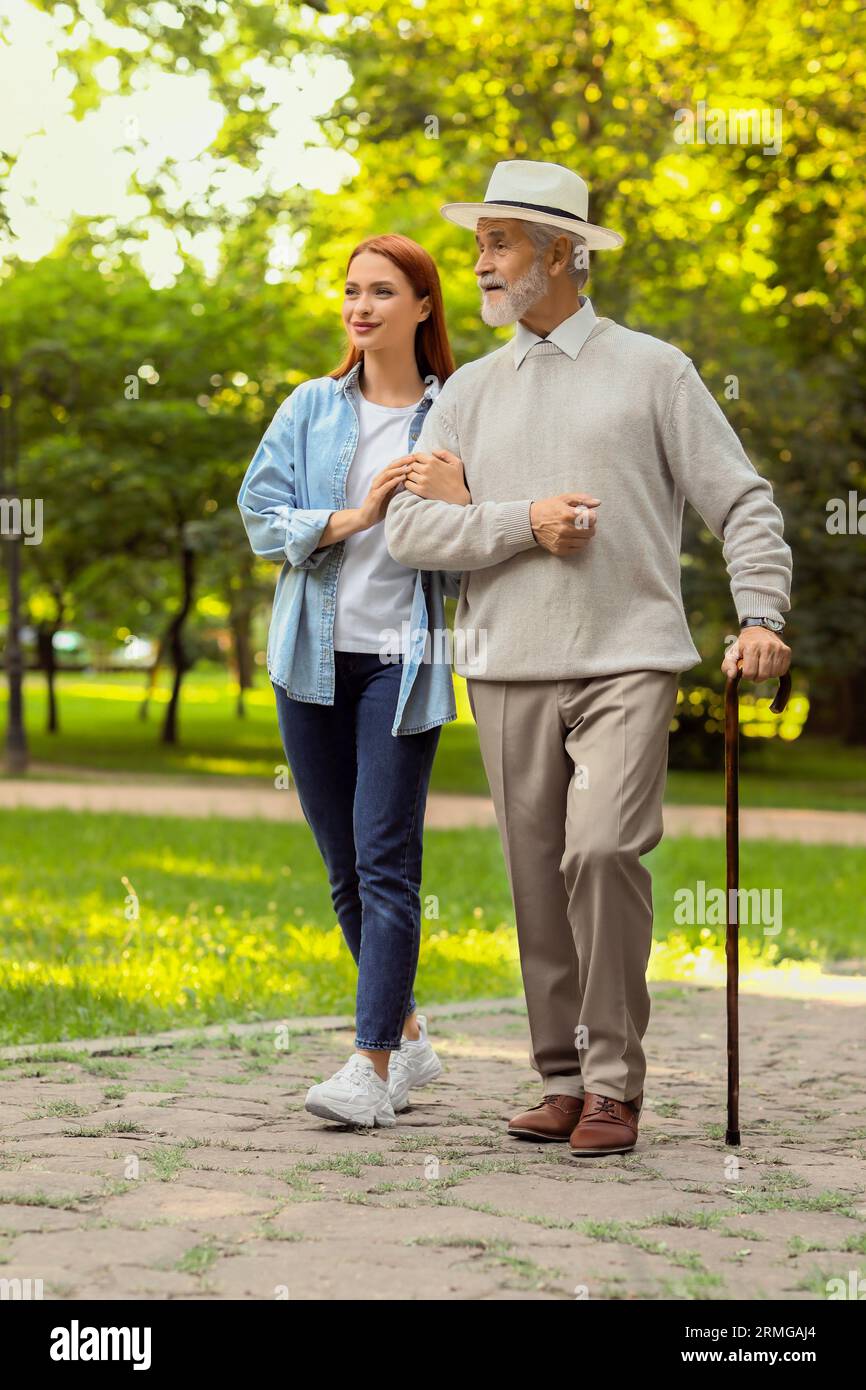 Senior man with walking cane and young woman in park Stock Photo - Alamy