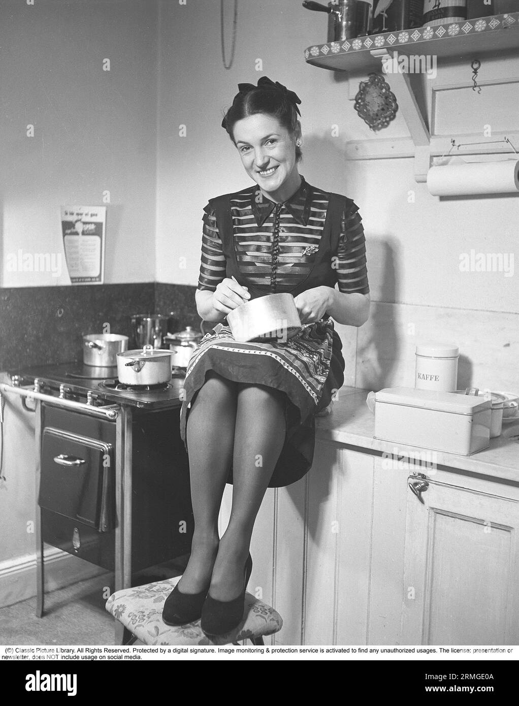 In the kitchen 1940s. Interior of a kitchen and a young woman smiles at ...