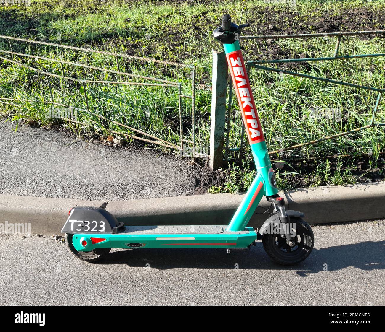 Green urban ecoscooter is standing near the sidewalk. Ukrainian kick