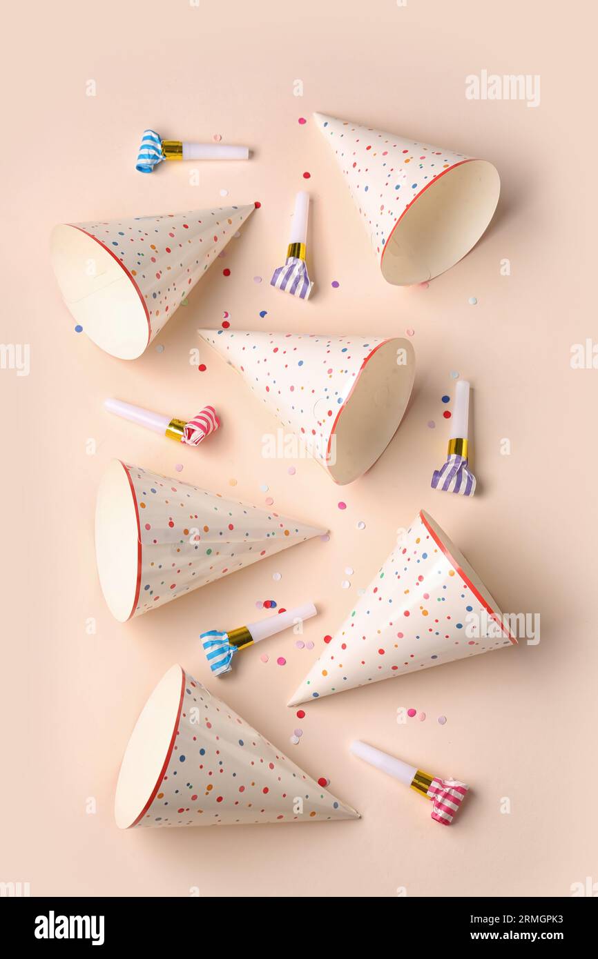 Party hats and whistles on pale orange background Stock Photo - Alamy