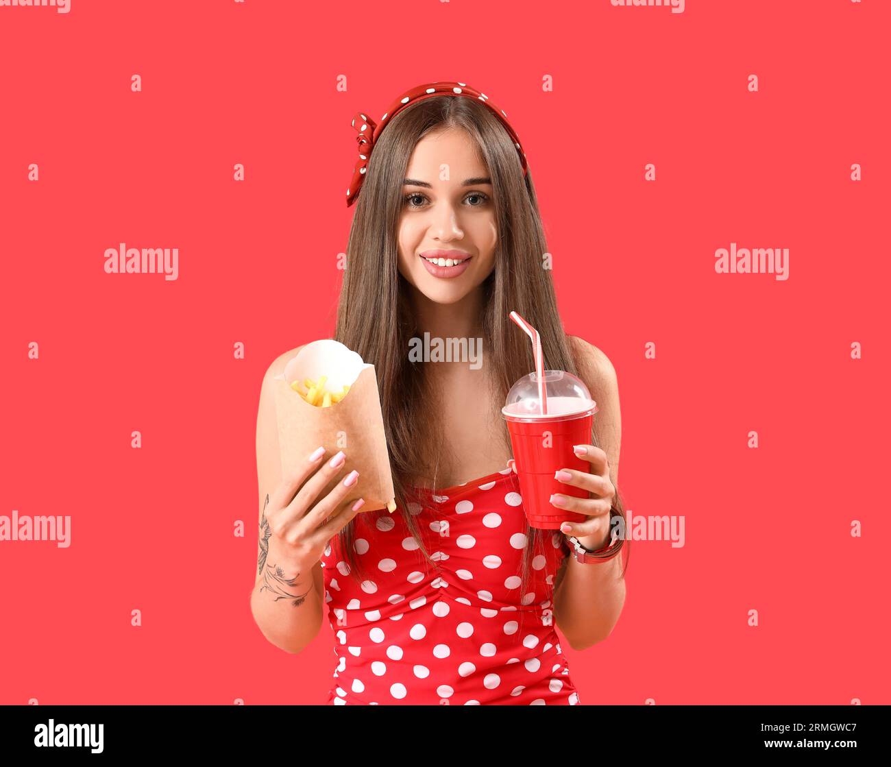 Beautiful young woman with french fries and cup of cola on red background Stock Photo