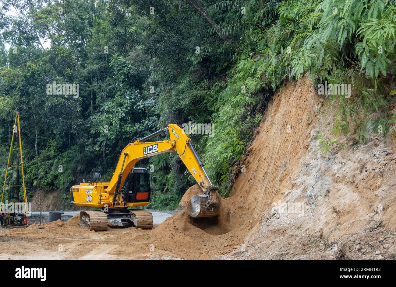 Road crew cleaning up a mountain road with an excavator. Sumatra, Indonesia. Stock Photo
