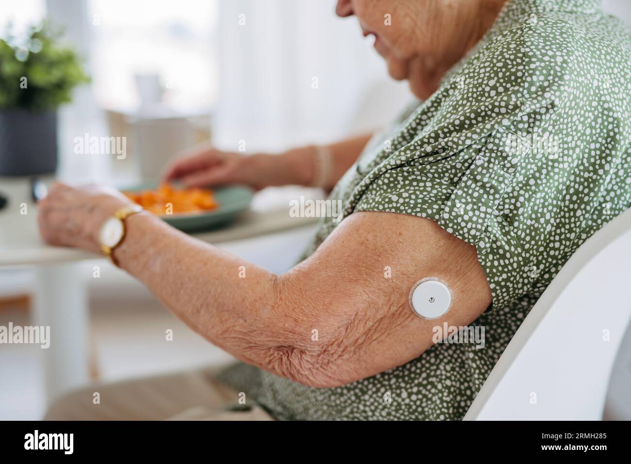 Close up of continuous glucose monitor on senior woman's upper arm