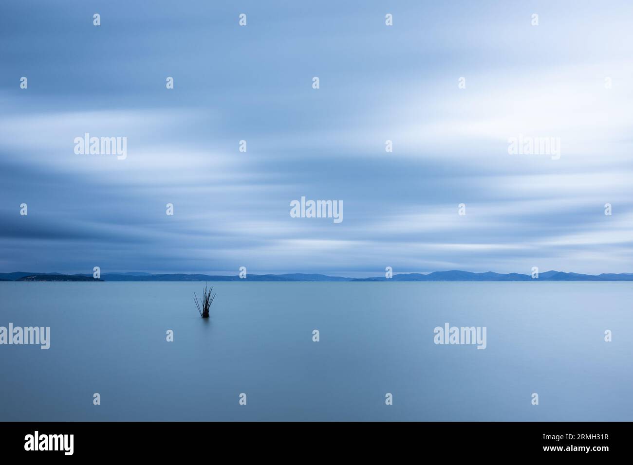 Minimalist view of fishing net poles on a lake, with perfectly still water  and empty sky at dusk Stock Photo - Alamy