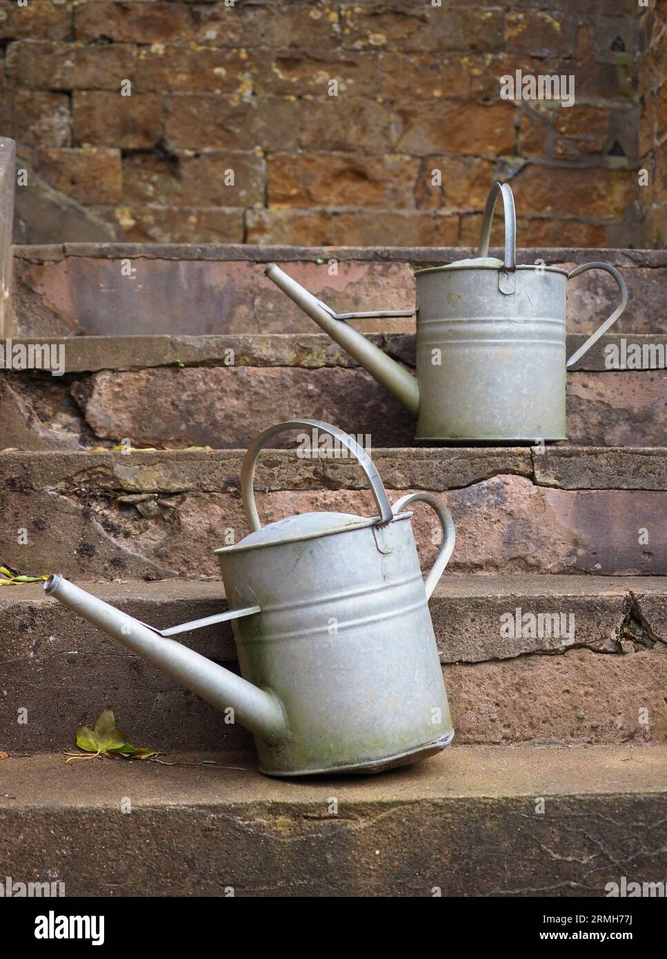 An antique watering cans on stone steps, Upton House, Warwickshire Stock Photo