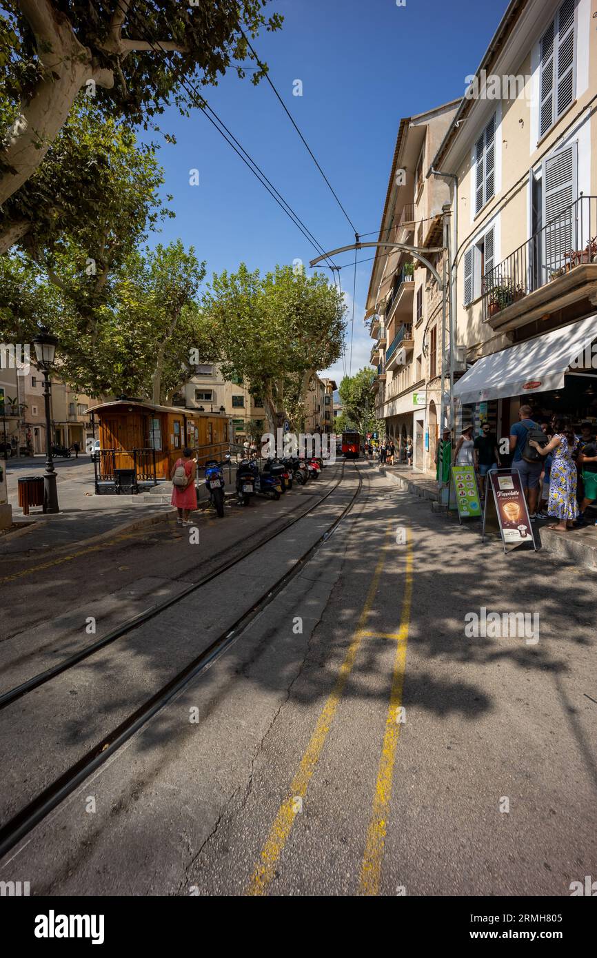 Wide shot of a street with a tram in the background and rails andf overhead power lines Stock Photo
