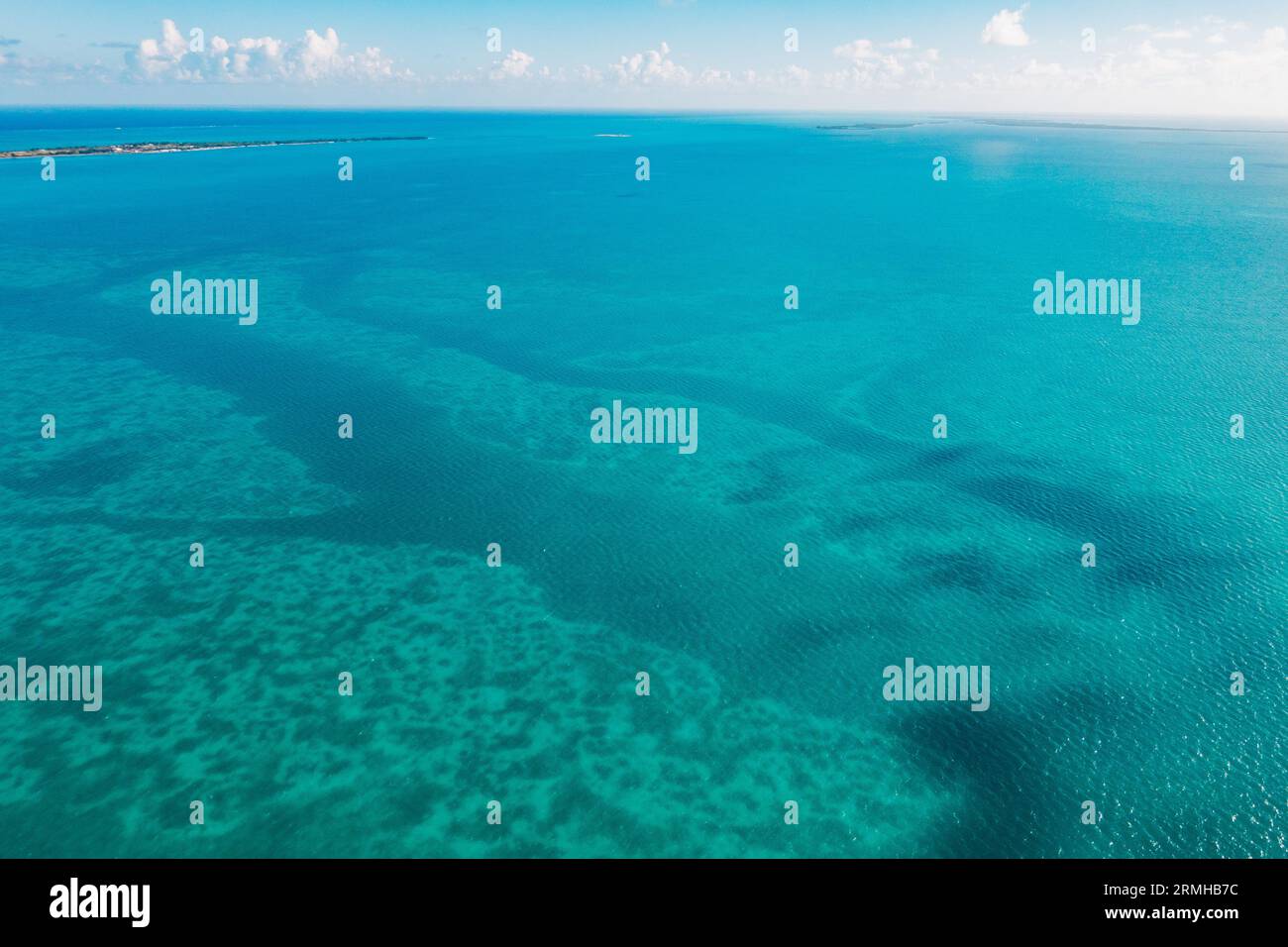 cloud shadows, different water, depths, and coral reefs create different shades of blue on the ocean off the coast of Belize Stock Photo