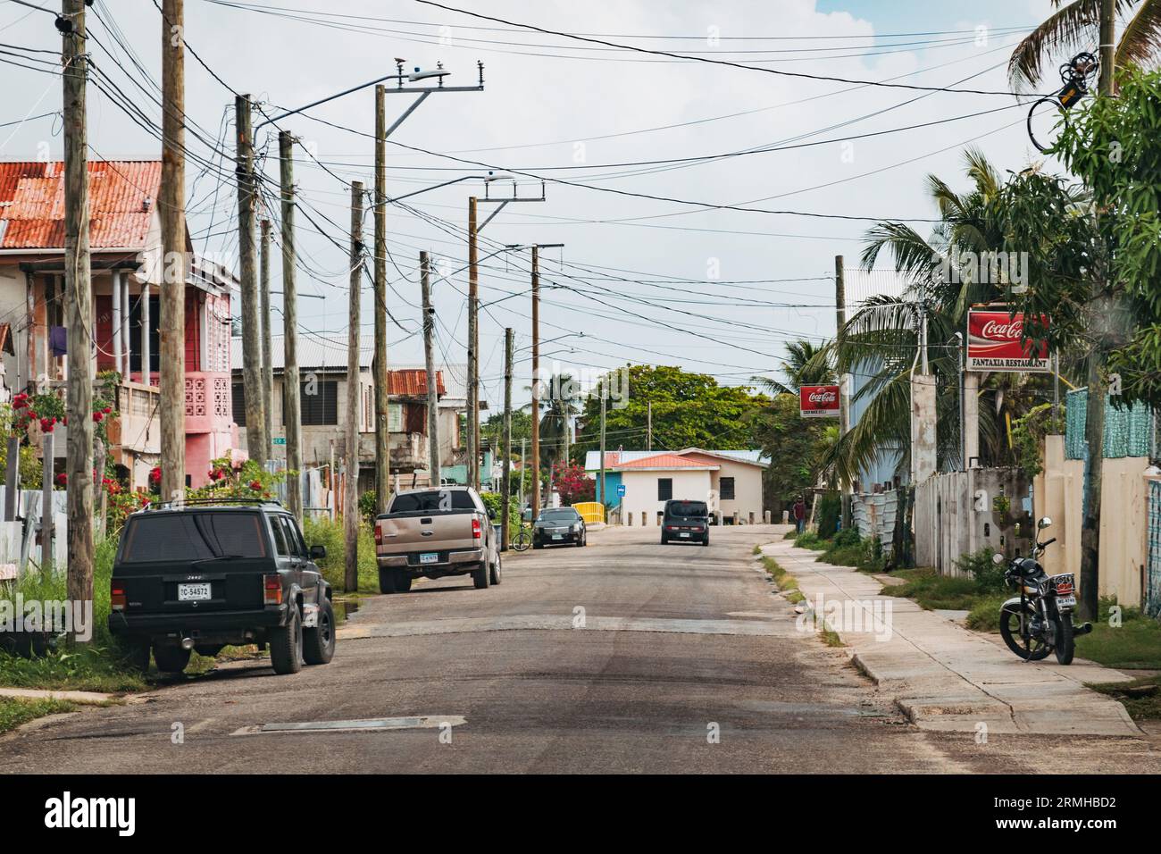 a quiet, empty suburban street in Belize City, Belize. Shops have Coca-Cola signs mounted out front Stock Photo