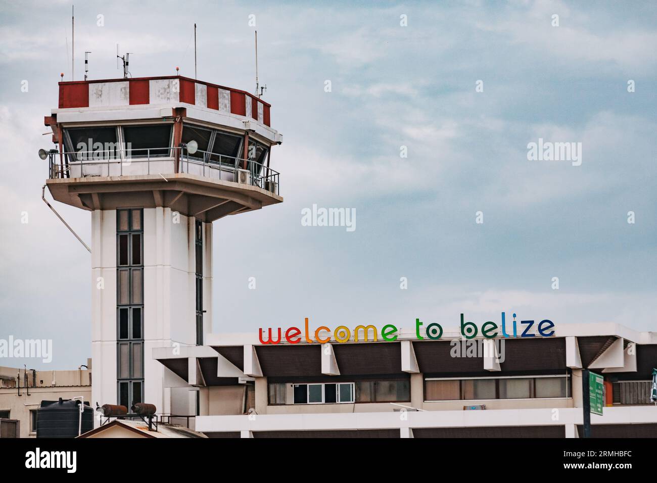 The control tower and airport building at Philip S.W. Goldson International Airport, Belize City. A sign on the terminal reads 'welcome to Belize' Stock Photo