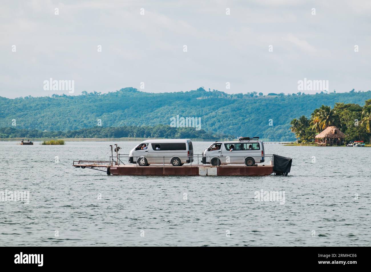 tourist vans get ferried on a barge across Lake Petén Itzá to the city of Flores, Guatemala Stock Photo