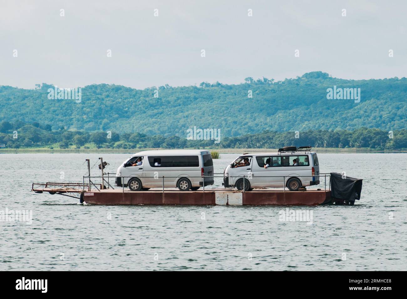 tourist vans get ferried on a barge across Lake Petén Itzá to the city of Flores, Guatemala Stock Photo