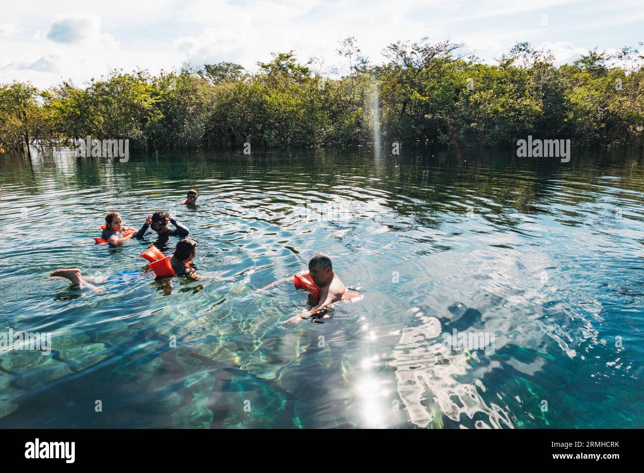 a family swim in the crystal clear waters of Crater Azul (the Blue Crater) in northern Guatemala Stock Photo