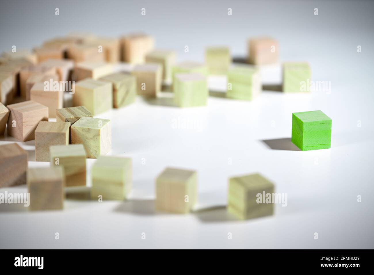 Thinking Green, even a single one can bring about change, green wooden cube affects the group of colorless blocks, beginning of a development, environ Stock Photo