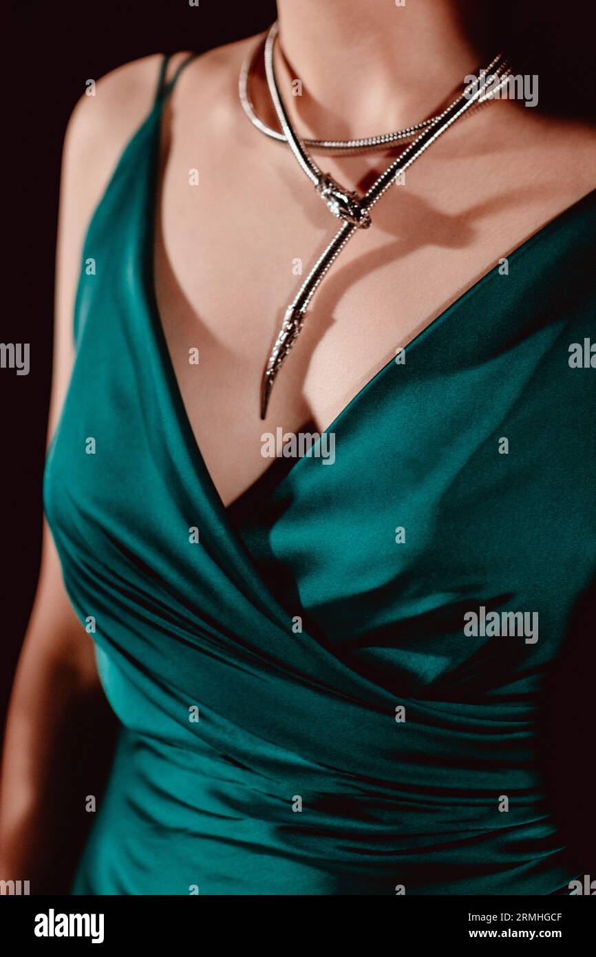 Female body in a silky elegant green dress with silver neck jewelry. Stylish clothing concept and fancy accessories Stock Photo