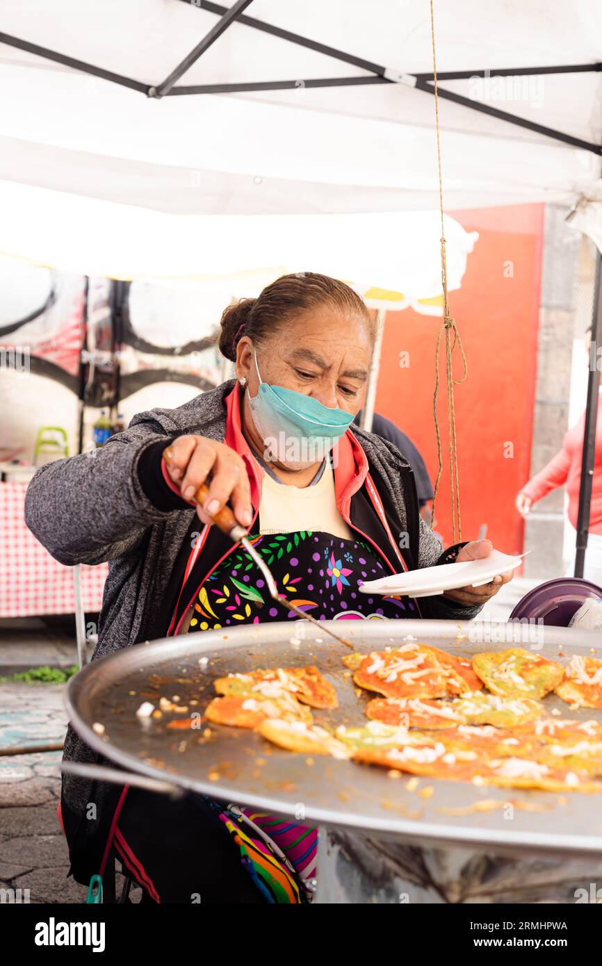 Senior lady prepares chalupas poblanas submerged in lard, Mexican food
