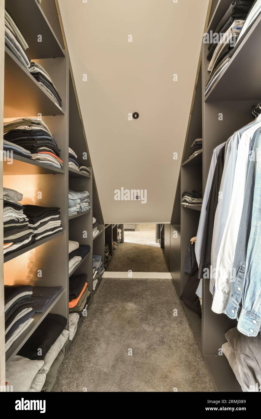 a walk in closet with lots of clothes on the shelves and hanging
