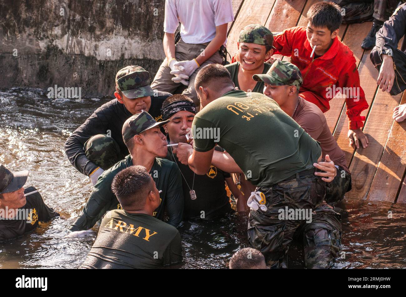 Thai military men take a cigarette brake while repairing a breach in the floodwall at the Phra Kanong Canal. Bangkok, Thailand. © Kraig Lieb Stock Photo