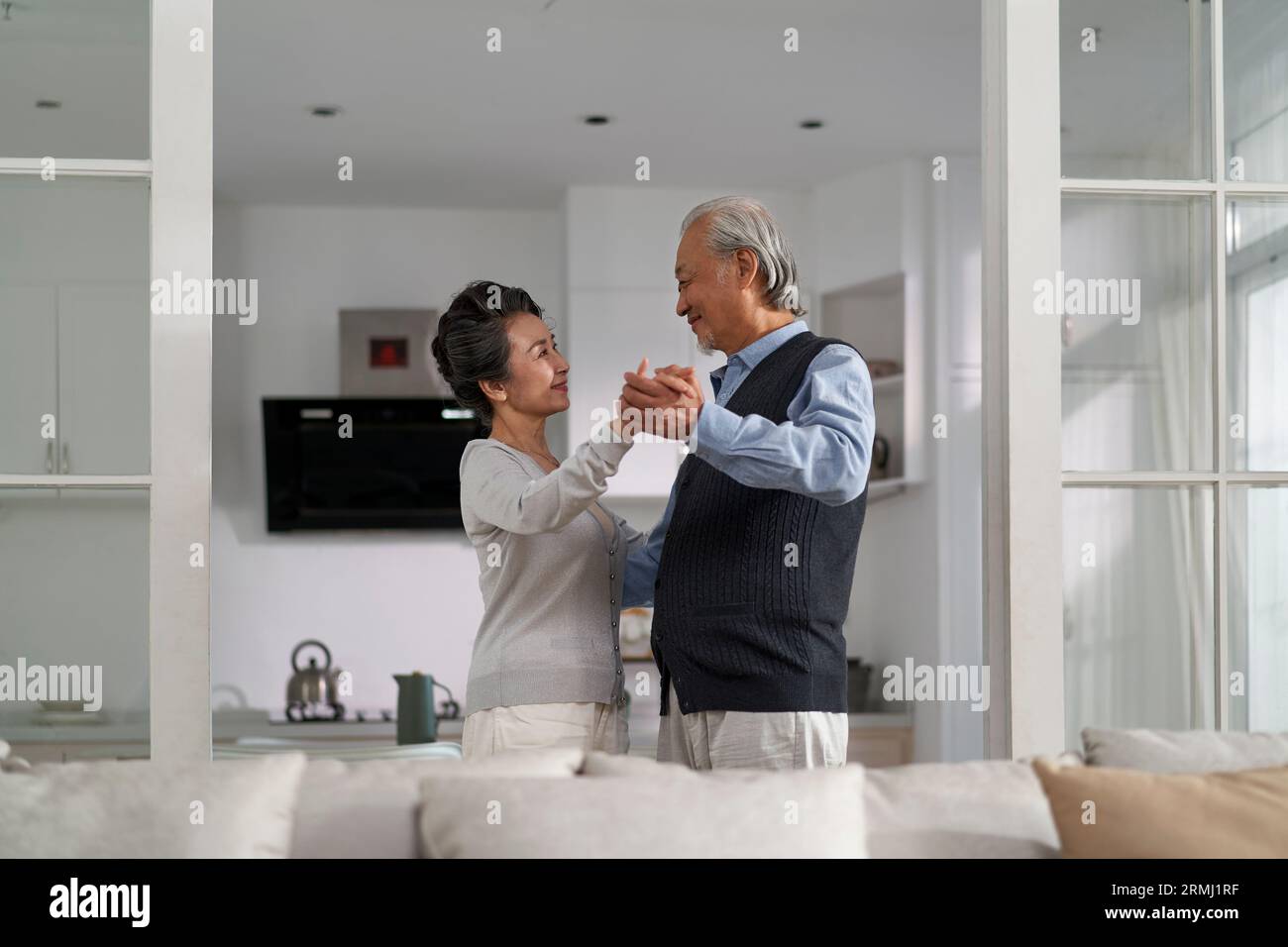loving romantic senior asian couple dancing in living room at home Stock Photo