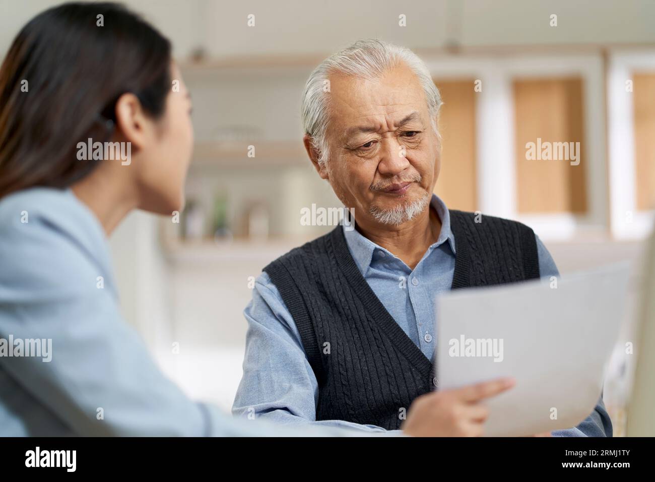 senior asian man appears to be confused by and suspicious at a sales person selling financial product Stock Photo